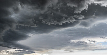 Hands holding large pile of hailstones that have damaged roof