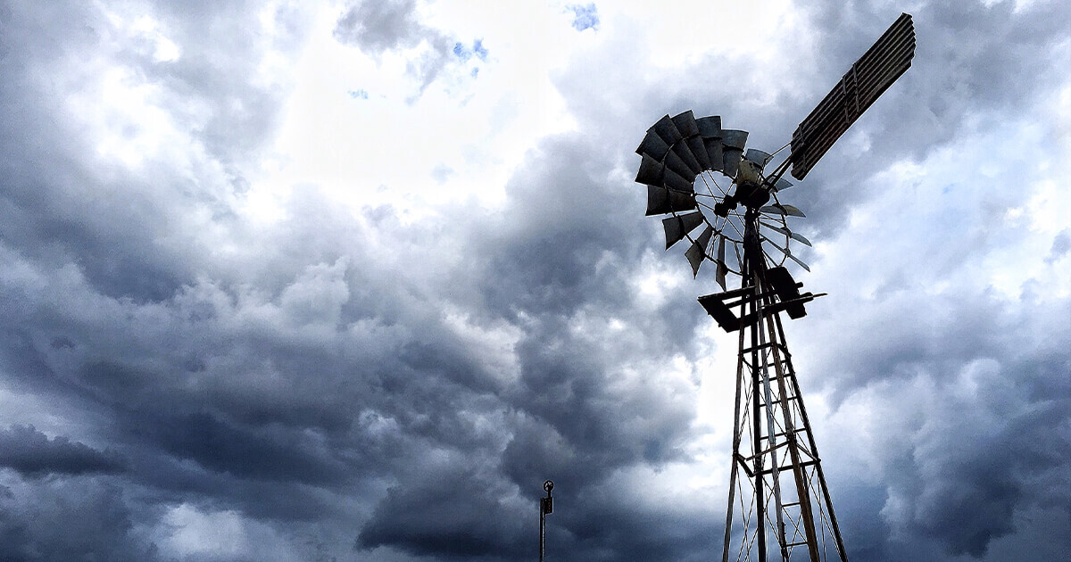 Large storm over farm with windmill in foreground