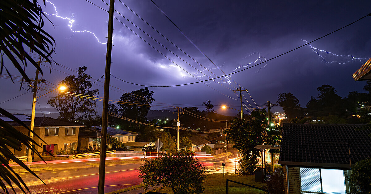 Lighting through storm clouds at night over suburban city